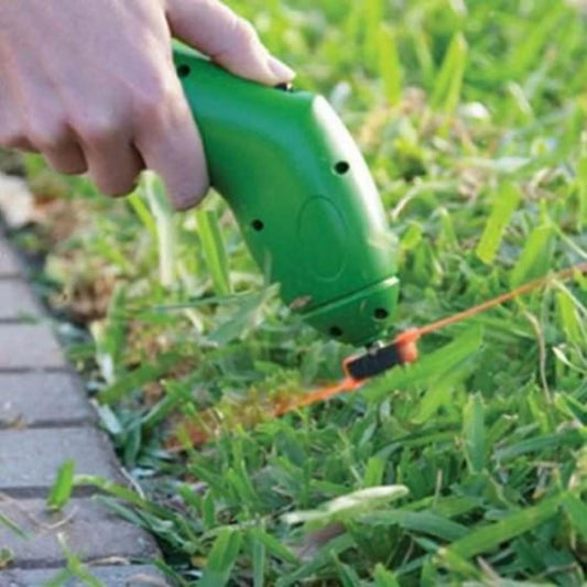 Person using a green string trimmer to cut grass along a sidewalk