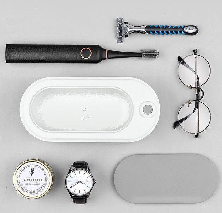 Collection of grooming and personal care items including a razor, electric shaver, glasses, and a watch on a gray background.