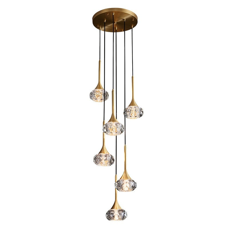 Gold pendant light fixture with crystal-like glass shades on a white background