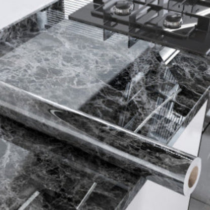 Close-up of a roll of marble-patterned paper with a cutting machine in the background.