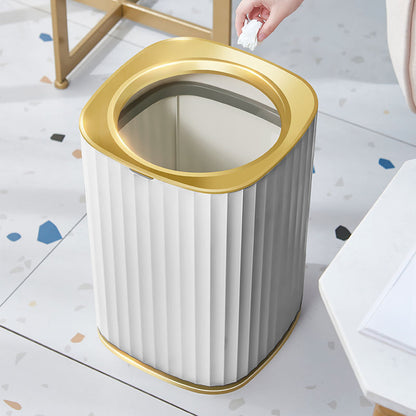 White trash bin with gold rim on a light-colored floor