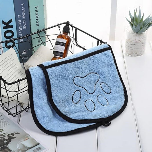 Blue towel with paw print design on a white surface with books and a plant in the background