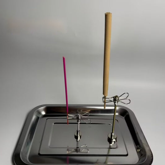 Incense sticks on a metal tray with a plain background