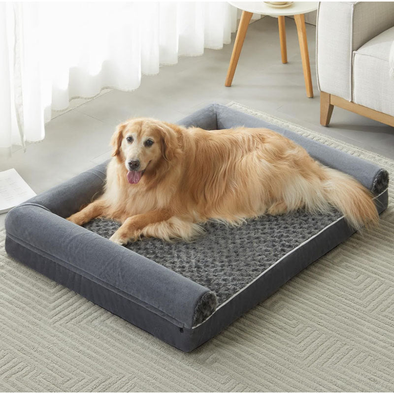 Dog lying on a large gray pet bed in a living room.