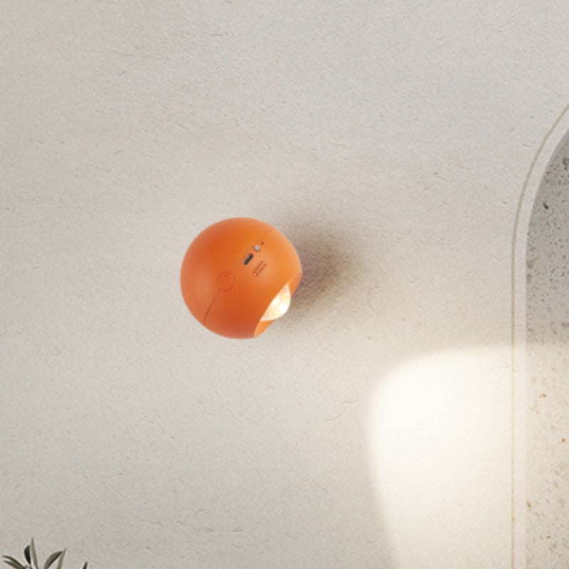Orange spherical wall light fixture on a white wall.
