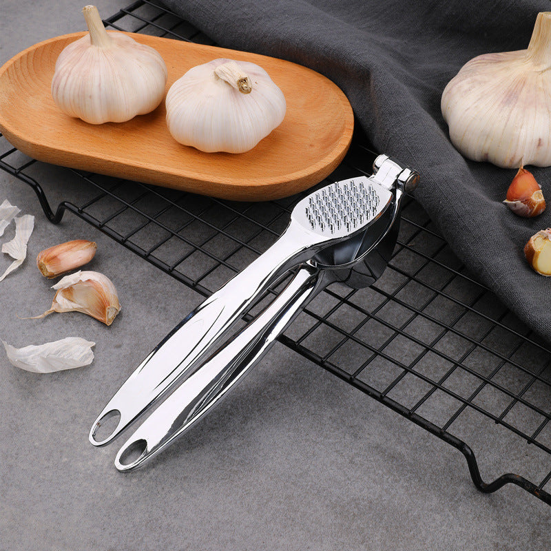 Garlic press on a cooling rack with garlic cloves around it.