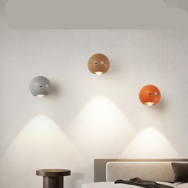 Three spherical wall lights in different colors on a neutral wall.