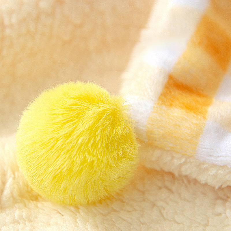 Close-up of a yellow plush ball on a soft beige background