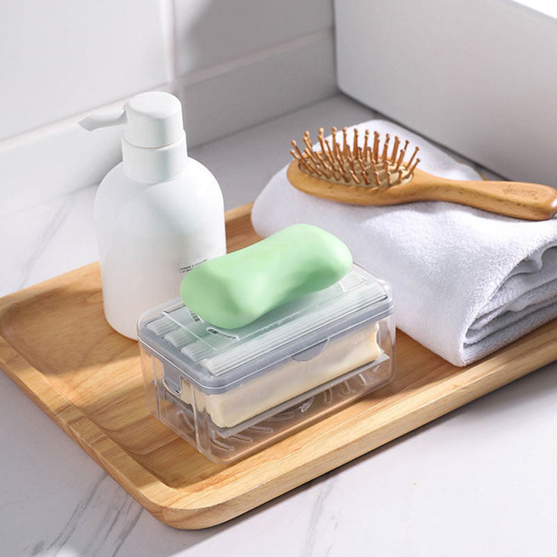 Wooden tray with soap, bottle, brush, and towel on a white surface