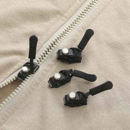 Close-up of zipper pullers on a beige fabric background