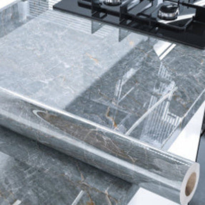 Roll of gray marble contact paper on a kitchen counter with a gas stove.