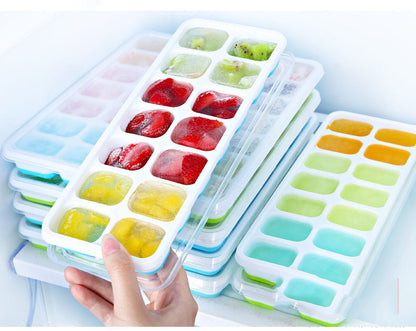Ice cube trays with frozen fruits and vegetables on a white background
