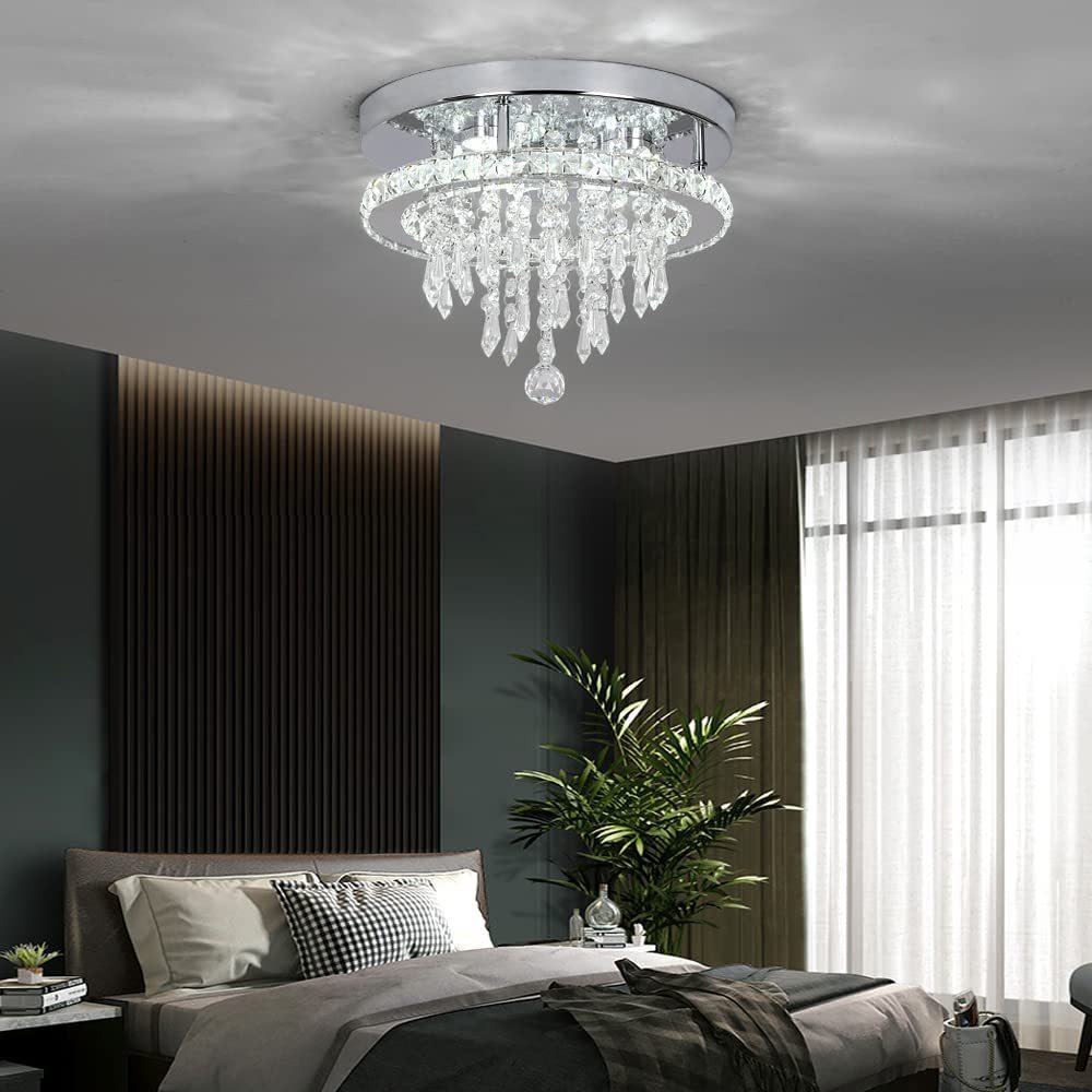 Chandelier hanging above a bed in a modern bedroom with dark walls and a large window.
