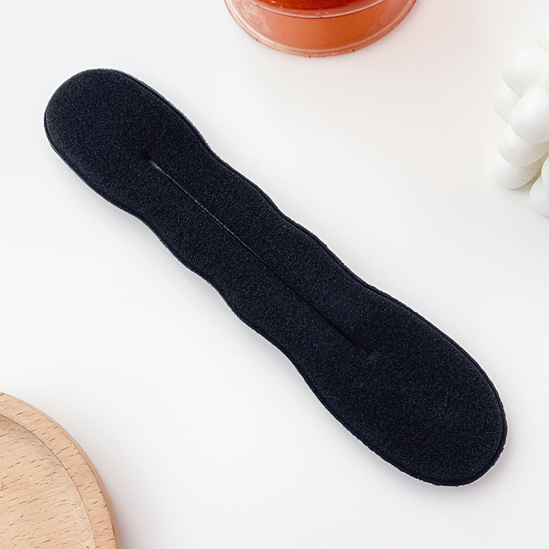 Black insole on a white surface with a small round object in the background