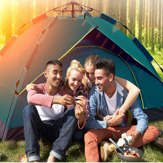 Four friends sitting in front of a tent, looking at a phone together, with a scenic background.